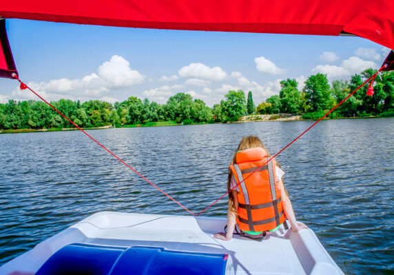 Young girl wearing life vest sitting at the back of a boat on the lake